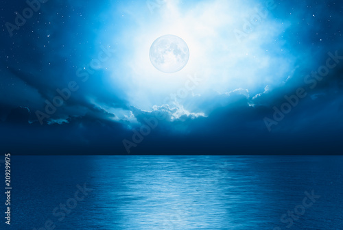 Night sky with full moon and reflection in sea    Elements of this image furnished by NASA   