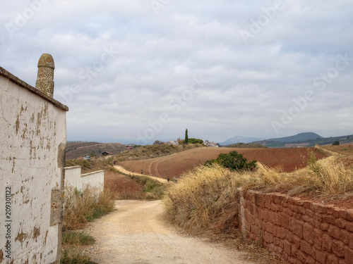 Pilgrims walk from Maneru to the medieval hilltop village Cirauqui - Navarre, Spain photo