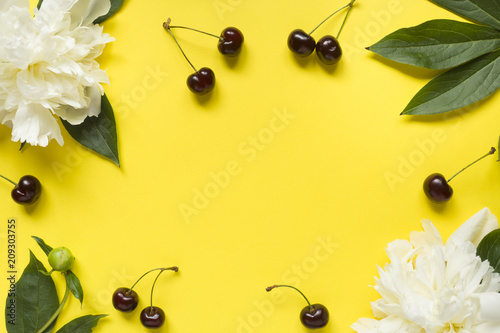 Frame from white flowers peony, Ripe cherries on a bright yellow background. Copy space