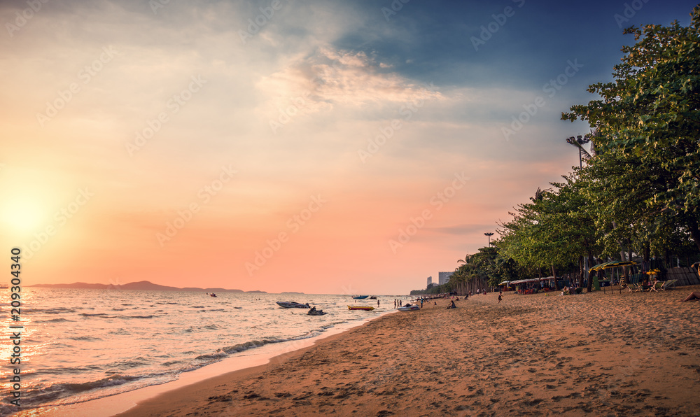 Fototapeta premium Beach with palm trees at sunset. Jomtien beach in Thailand.