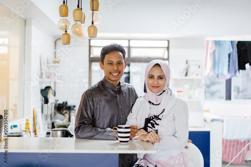 Photography A young Muslim Malay couple sit at a table top counter and enjoy a coffee early in the morning when they break fast