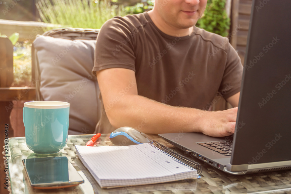 Mann arbeitet im eigenen Garten am Notebook Mann arbeitet im eigenen Garten am Notebook
