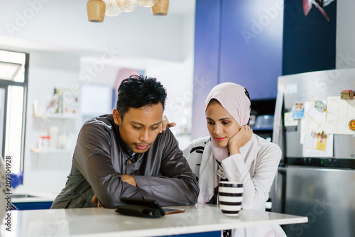 A young Muslim Malay couple sit at a table top counter and enjoy a coffee early in the morning when they break fast.  photo