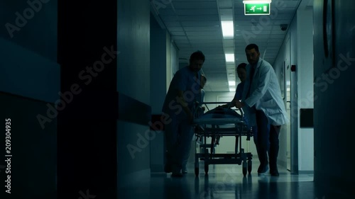 Emergency Department: Doctors, Nurses and Paramedics Push Gurney / Stretcher with Seriously Injured Patient towards the Operating Room. Shot on RED EPIC-W 8K Helium Cinema Camera.