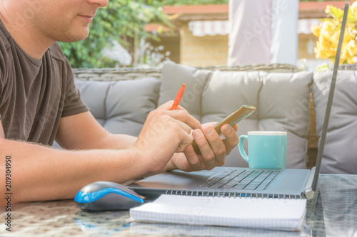 Mann kommuniziert im Home Office per Smartphone mit Kollegen photo