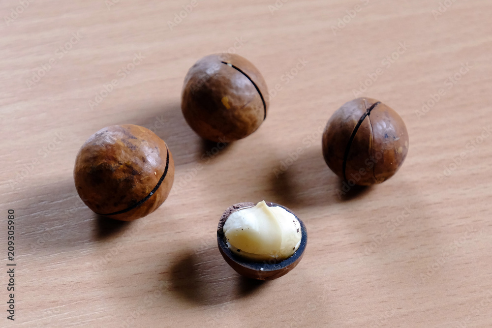 Obraz premium Macadamia nuts in shell on wooden table