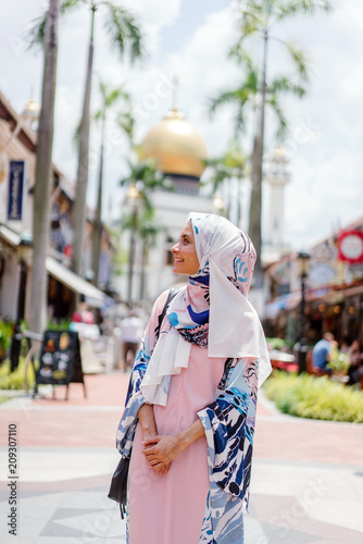 A portrait of Malay woman being amazed by the things she cansee around her. She is wearing an Abaya dress and head scarves that shows that she is a Muslim and a religious woman.