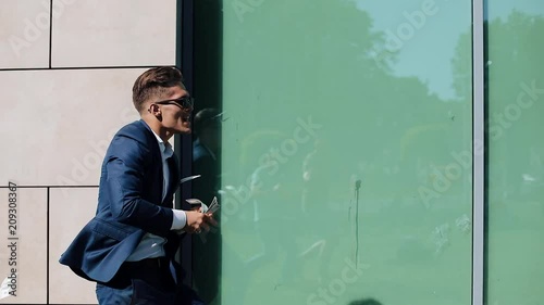 Young happy businessman scatter the dollars and funny dancing in the street. Money rain, falling dollars. It is located near the office center, slow motion. Successful business. Shot on Red Epic