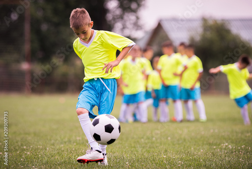 Boy kicking football on the sports field © Dusan Kostic