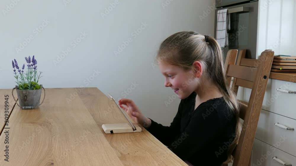 Pretty Young Girl Using A Smartphone In The Kitchen, Smiling. Pretty Young Girl Using A Smartphone In The Kitchen, Smiling.