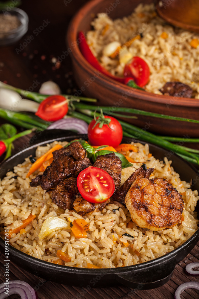 The concept of oriental cuisine. Homemade Uzbek pilaf from lamb served in cast iron cookware. Copy space.