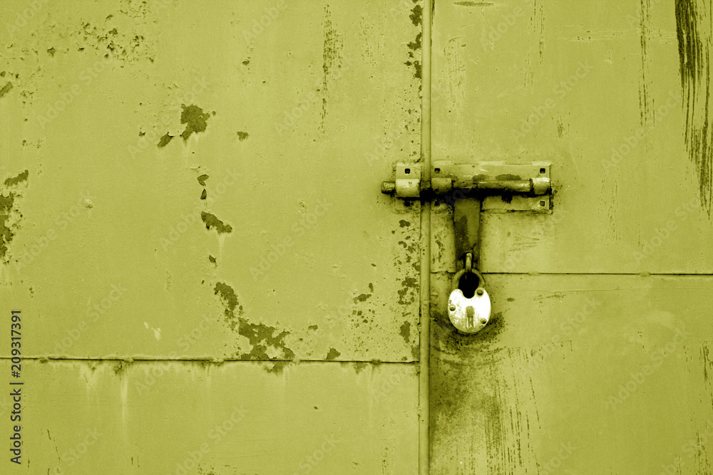 Old padlock on metal gate in yellow color.