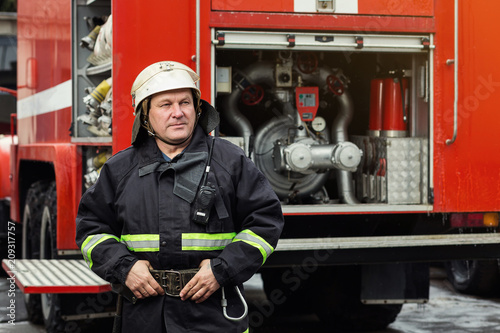 Fireman (firefighter) in action standing near a firetruck. Emergency safety. Protection, rescue from danger.