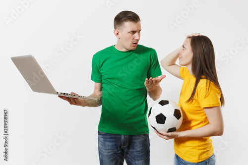 Shocked couple woman man, football fans in yellow green t-shirt cheer up support team with soccer ball, watching game on pc laptop isolated on white background. Sport family leisure lifestyle concept.
