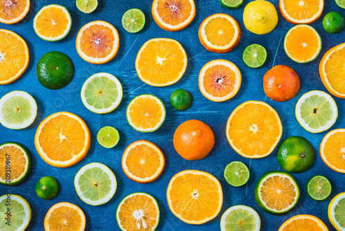 Citrus pattern on blue background. Assorted citrus fruits. Slices of orange  tangerine  lemon  lime. Top view.