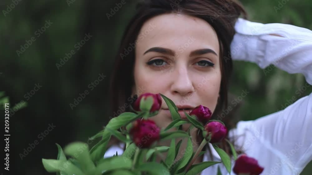 beautiful woman with pink peonies. girl smelling flowers and look sensual.
