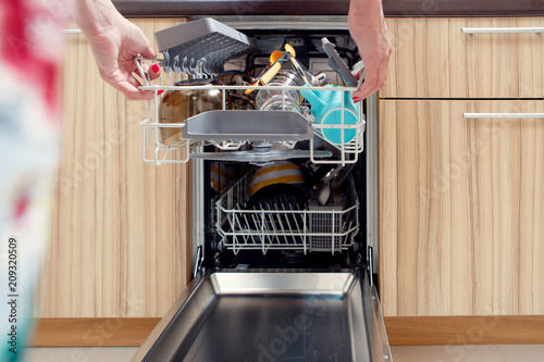 Image of girl's hand opening dishwasher with dirty dishes