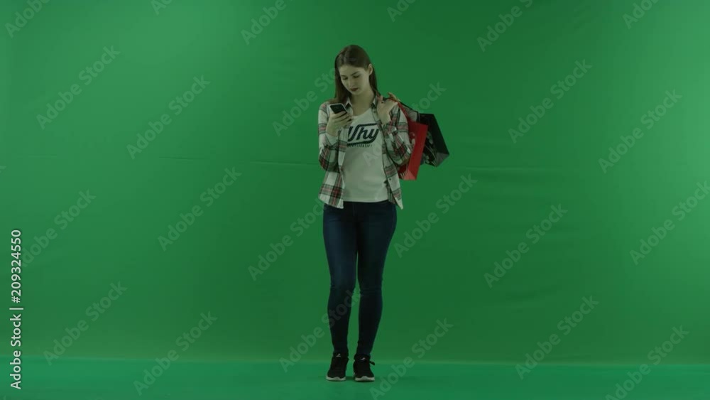 the girl stands with bags on her shoulder and writes something in her phone on green screen the girl stands with bags on her shoulder and writes something in her phone on green screen