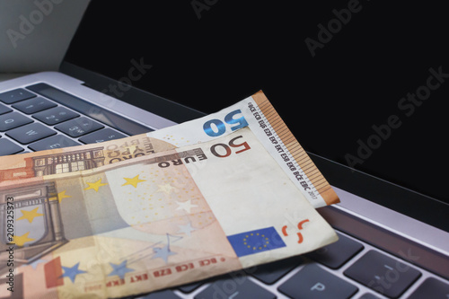 banknotes of 50 euros on the laptop keyboard