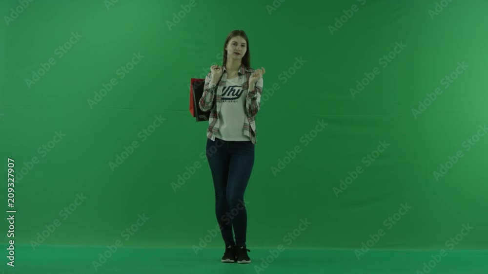 girl with packages on her shoulder, chooses something from the screen on the green backgroung girl with packages on her shoulder, chooses something from the screen on the green backgroung