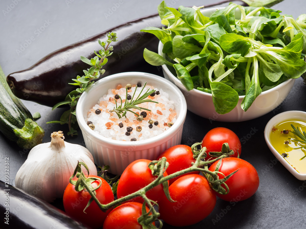 Mix of raw vegetables with salt, spices on dark background. Clean healthy eating concept Mix of raw vegetables with salt, spices on dark background. Clean healthy eating concept