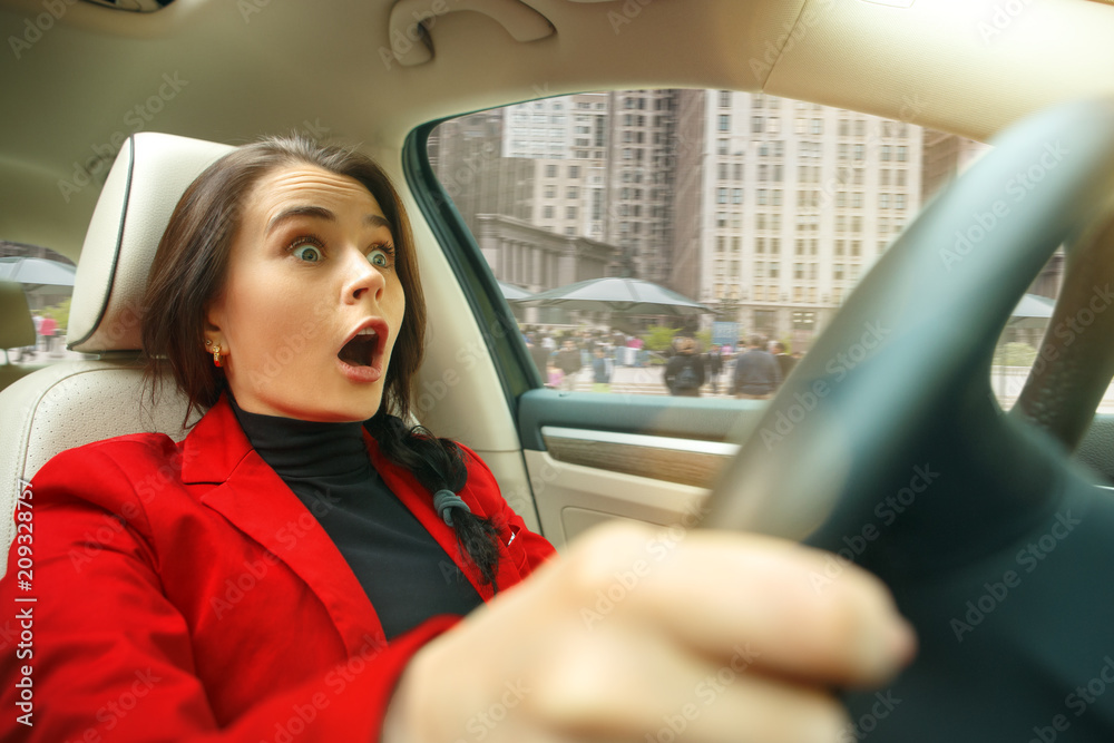 Driving around city. Young attractive woman driving a car