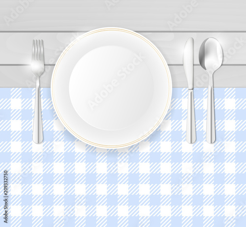 Porcelain plate and stainless cutlery on table with blue cloth