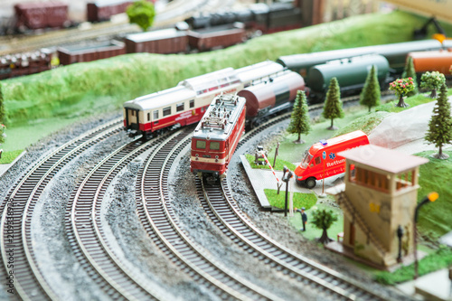 A breadboard model of a railway with a locomotive, wagons, trees, buildings, lawns. View from above.