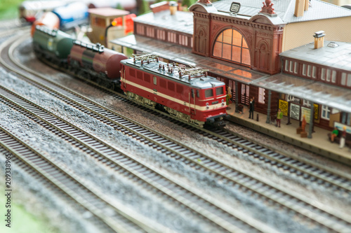 A breadboard model of a railway with a locomotive, wagons, trees, buildings, lawns. View from above.