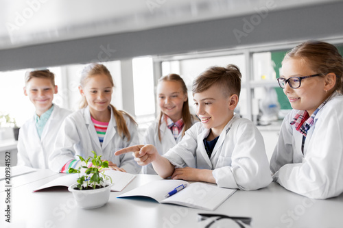 education, science and school concept - kids or students with plant at biology class photo