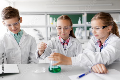 education, science, chemistry and children concept - kids or students with test tube making experiment at school laboratory