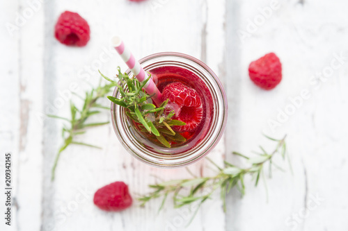 Glass bottle of homemade raspberry lemonade flavored with rosemary