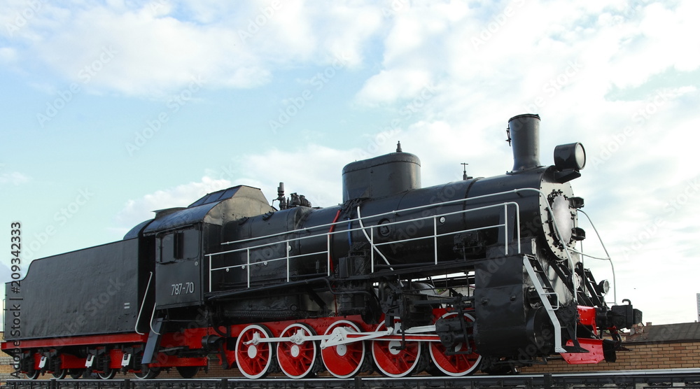Naklejka premium Black vintage steam locomotive with red wheels on the railway.