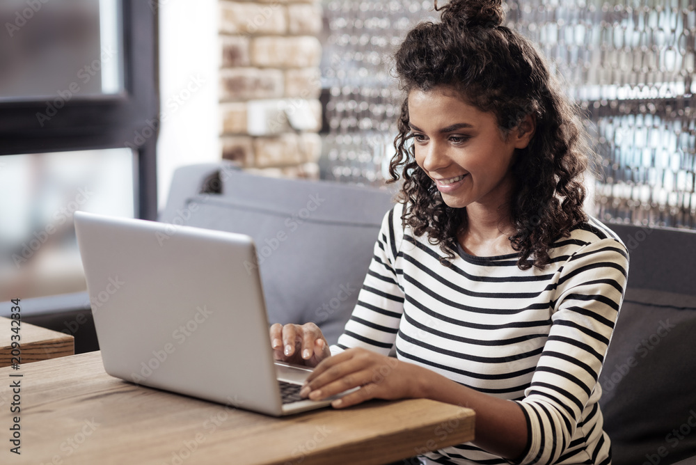 Professional freelancer. Positive happy woman sitting in the cafe while working on a laptop Professional freelancer. Positive happy woman sitting in the cafe while working on a laptop