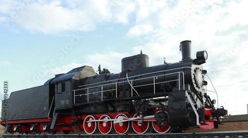 Black vintage steam locomotive with red wheels on the railway.