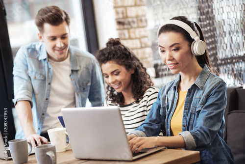 Wallpaper Mural Focused on work. Happy positive woman wearing headphone while working on the laptop Torontodigital.ca