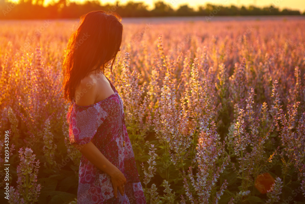 portrait of a girl in a blooming field in the sun at sunset, the concept of relaxation