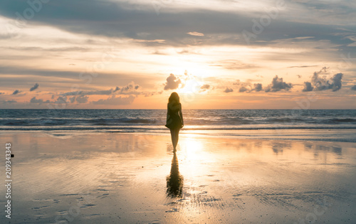 Silhueta de mulher caminhando para a luz, pôr do sol, Bali, Seminyak Beach, Indonesia photo