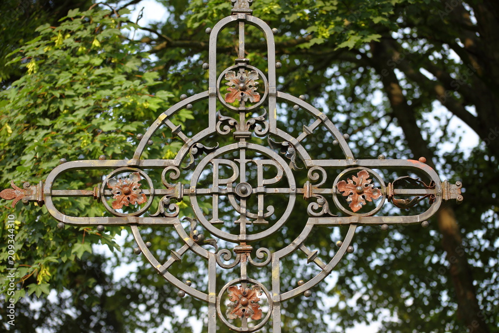 forged cross RIP against blurred foliage