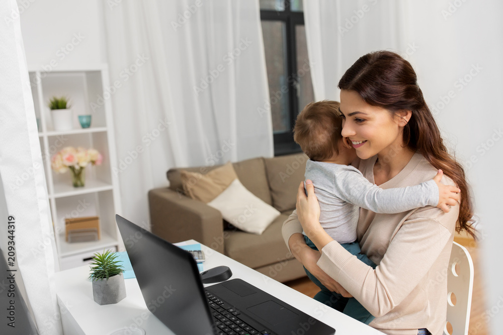 motherhood, multi-tasking, family and people concept - happy mother with baby and laptop working at home