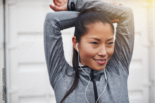 Young Asian woman stretching and listening to music before joggi