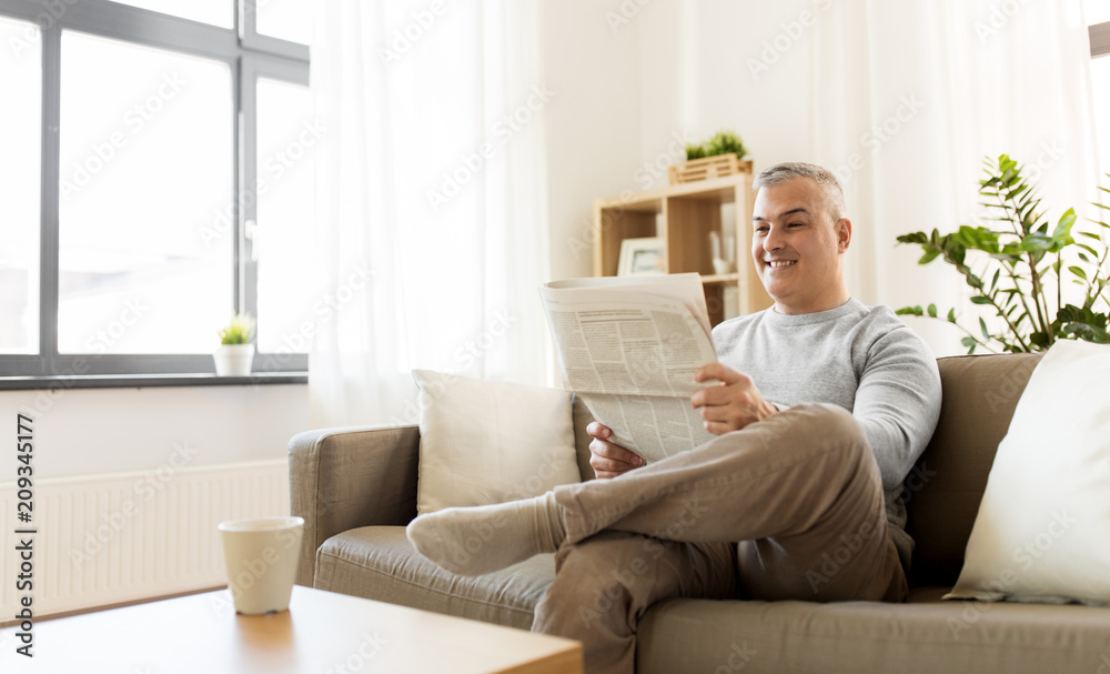 leisure, information, people and mass media concept - happy smiling man reading newspaper at home leisure, information, people and mass media concept - happy smiling man reading newspaper at home