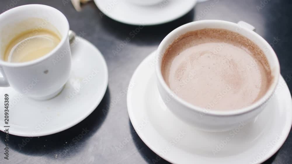 Hot chocolate being stirred with a spoon before a young man sips from the cup Hot chocolate being stirred with a spoon before a young man sips from the cup