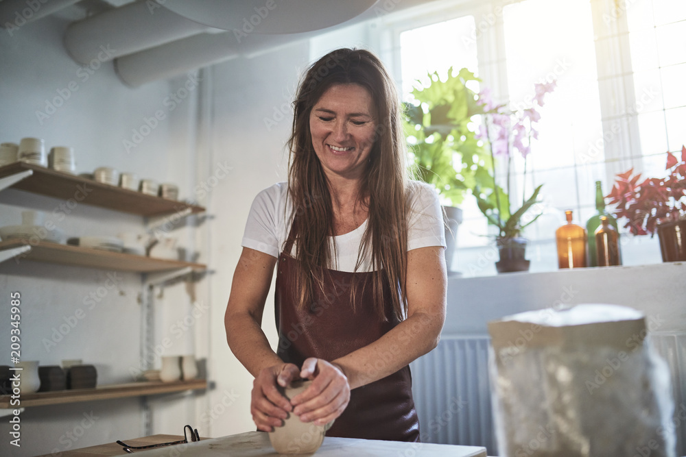 Smiling artisan working with clay in her ceramic workshop Smiling artisan working with clay in her ceramic workshop