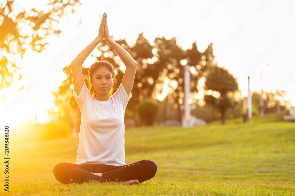 Pretty asian woman doing yoga exercises in the park