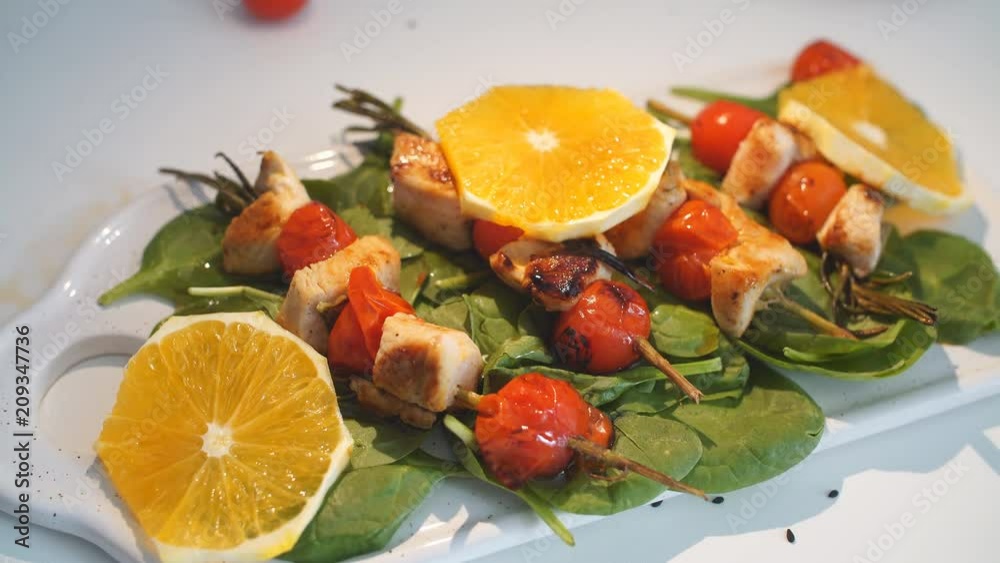 Chicken kebabs served with tomato cherry and greenery Chicken kebabs served with tomato cherry and greenery