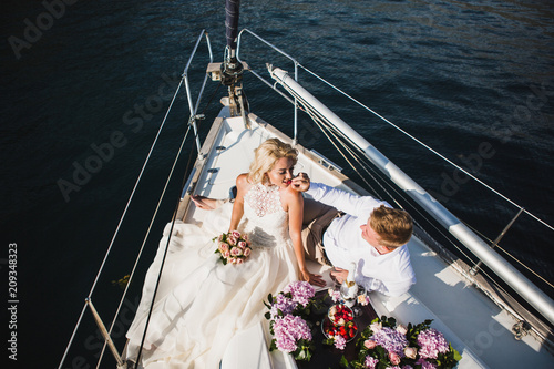 Beautiful stylish bride and groom on the luxury yacht traveling together on a warm summer day