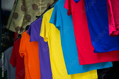 Multi color of t-shirts hanging on clothesline for sale in the shop.
