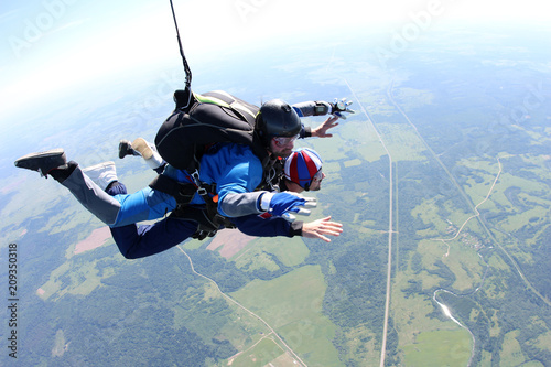 Skydiving. Two men are flying in the blue sky.