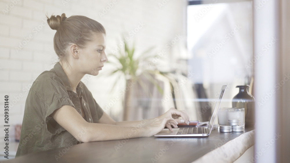A young pretty serious girl dressed in a green shirt with a laptop sitting at a table A young pretty serious girl dressed in a green shirt with a laptop sitting at a table